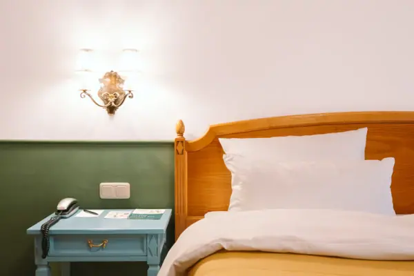 Hotelzimmer HENRI Garmisch-Partenkirchen Ein Bett mit Nachttisch und Telefon.