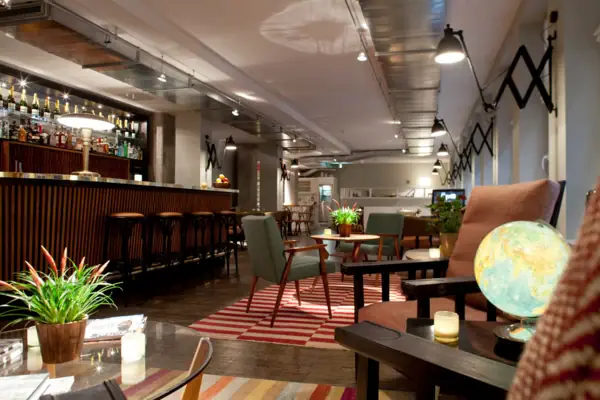 Rezeption und Loungebereich im HENRI Hamburg Ein Raum mit einer Bar und Sesseln.
