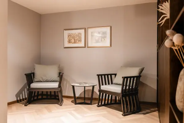 Sitzecke im Wellnessbereich Ein Raum mit Stühlen und einem Tisch, ausgestattet mit einem Sofa, Holzboden und einem Kaffeetisch.