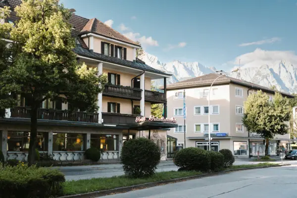 Außenansicht HENRI Hotel Garmisch-Partenkirchen Außenansicht HENRI Hotel Garmisch-Partenkirchen mit Bäumen und einer Straße.
