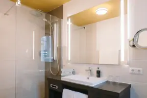 Ein Badezimmer mit Waschbecken und Spiegel im HENRI Hotel Garmisch-Partenkirchen.