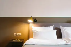 Ein Bett mit weißen Kissen und einer Lampe im HENRI Hotel Garmisch-Partenkirchen.