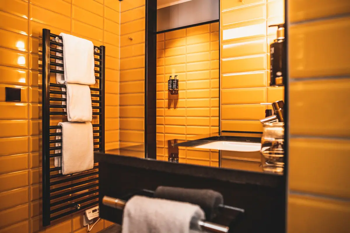 Badezimmer mit gelben Fliesenwänden und einem Spiegel