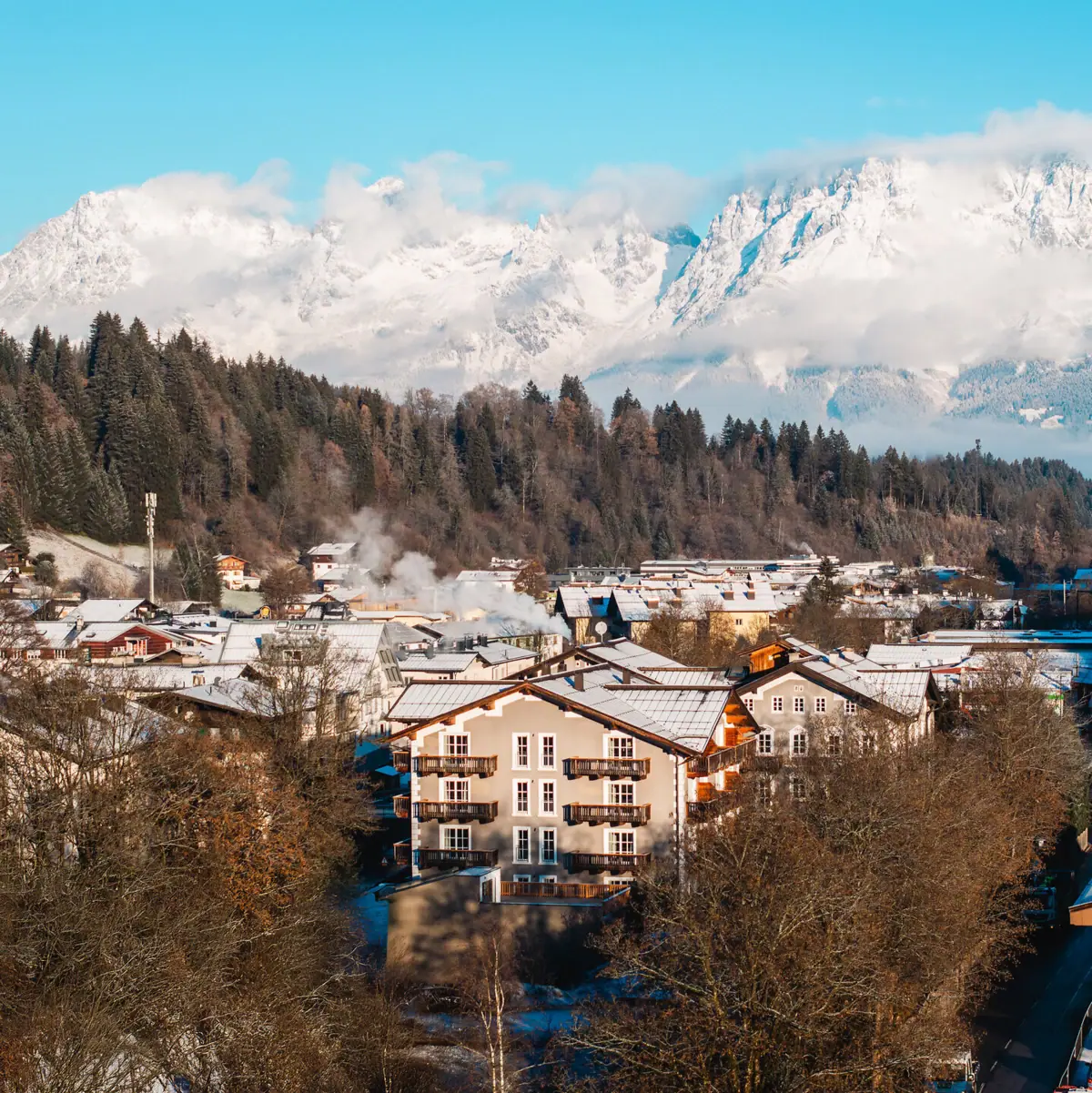 Ort Kitzbühel im Winter mit schneebedeckten Bergen im Hintergrund.
