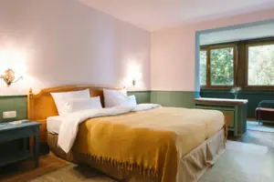 Ein Hotelzimmer im HENRI Hotel Garmisch-Partenkirchen mit einem Bett vor einer grün-weißen Wand.