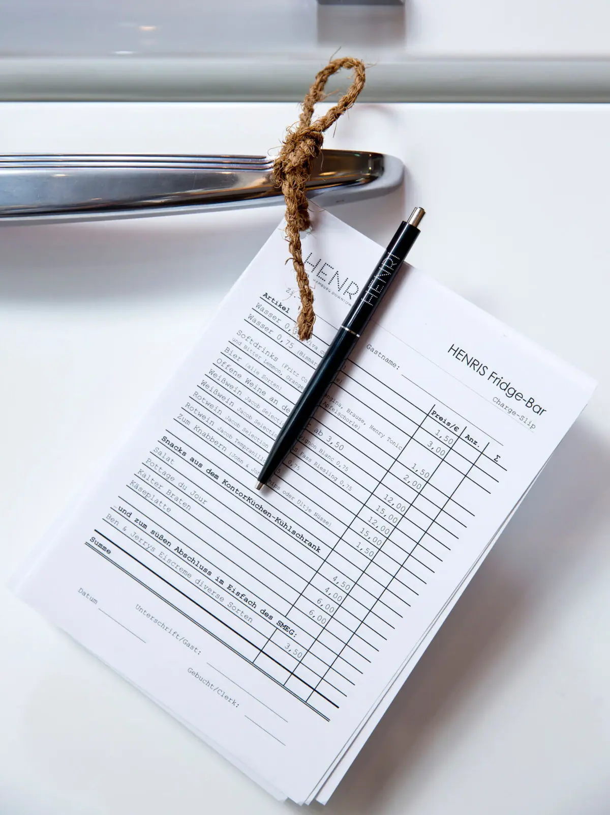 HENRIS Fridge Bar Ein Stift auf einem Blatt Papier hängt an einer Kühlschranktür.