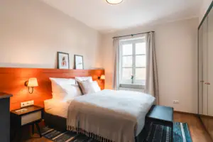 Bett mit Holz-Kopfteil und Lampe im Schlafzimmer.