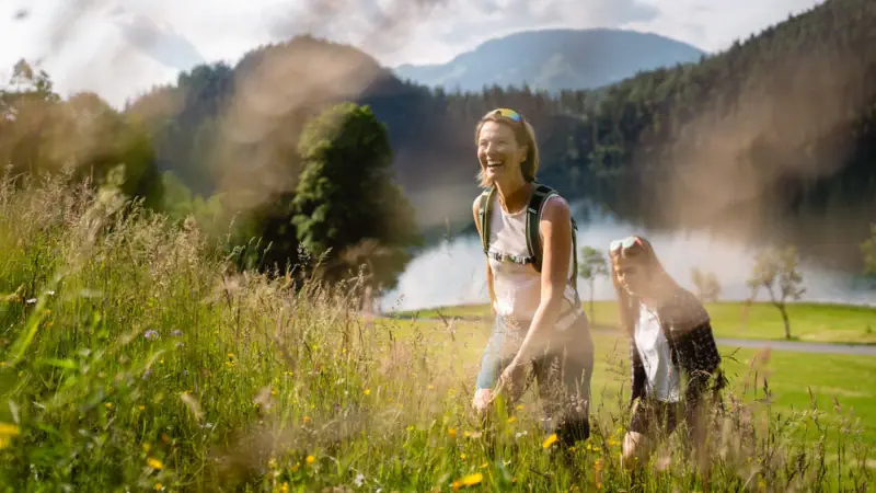 Zwei Frauen in einem Feld mit Gras und Pflanzen unter freiem Himmel.