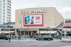 Die markante Fassade des historischen Zoo Palast Kinos in Berlin bei Tag mit aktueller Filmwerbung und Stadtverkehr im Vordergrund