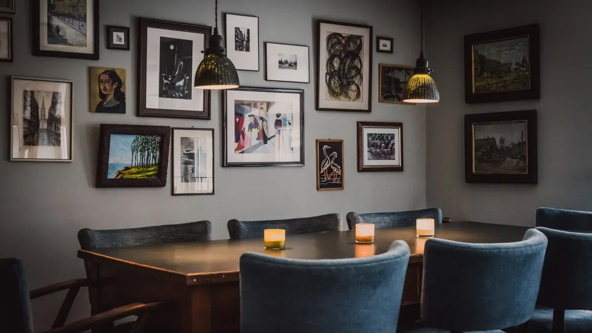 Ein Tisch mit Kerzen und Stühlen in der Kontorküche mit Bildern an der Wand.