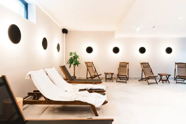 Liegestühle im Poolbereich Ein Raum mit Stühlen und einer Pflanze.