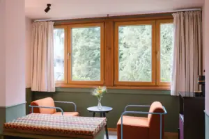 Eine Sitzecke mit zwei Sesseln vor einem Fenster in dem Hotelzimmer Chambre im HENRI Hotel Garmisch-Partenkirchen.