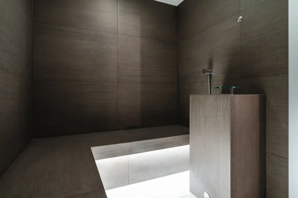 Dampfbad im HENRI Kitzbühel Ein dunkles Badezimmer mit quadratischem Objekt.