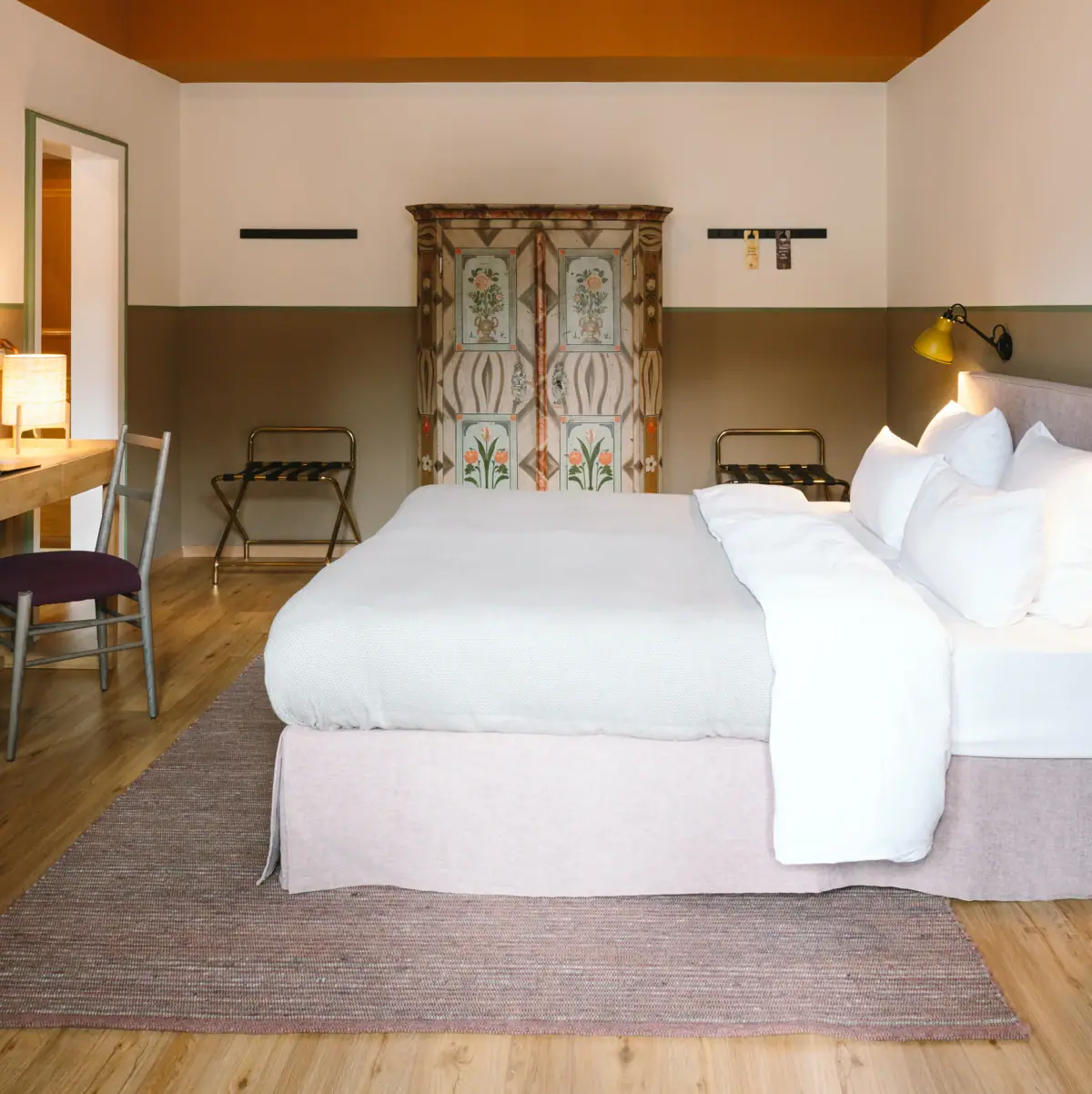 Zimmer HENRI Garmisch-Partenkirchen Ein schönes Hotelzimmer im HENRI Garmisch-Partenkirchen mit einem Bett und einem Schreibtisch.