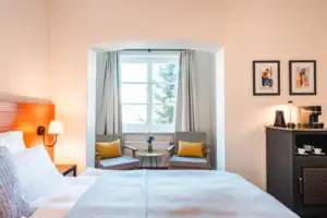 Schlafzimmer mit Bett und Stühlen, inklusive Nachttisch und Kissen.