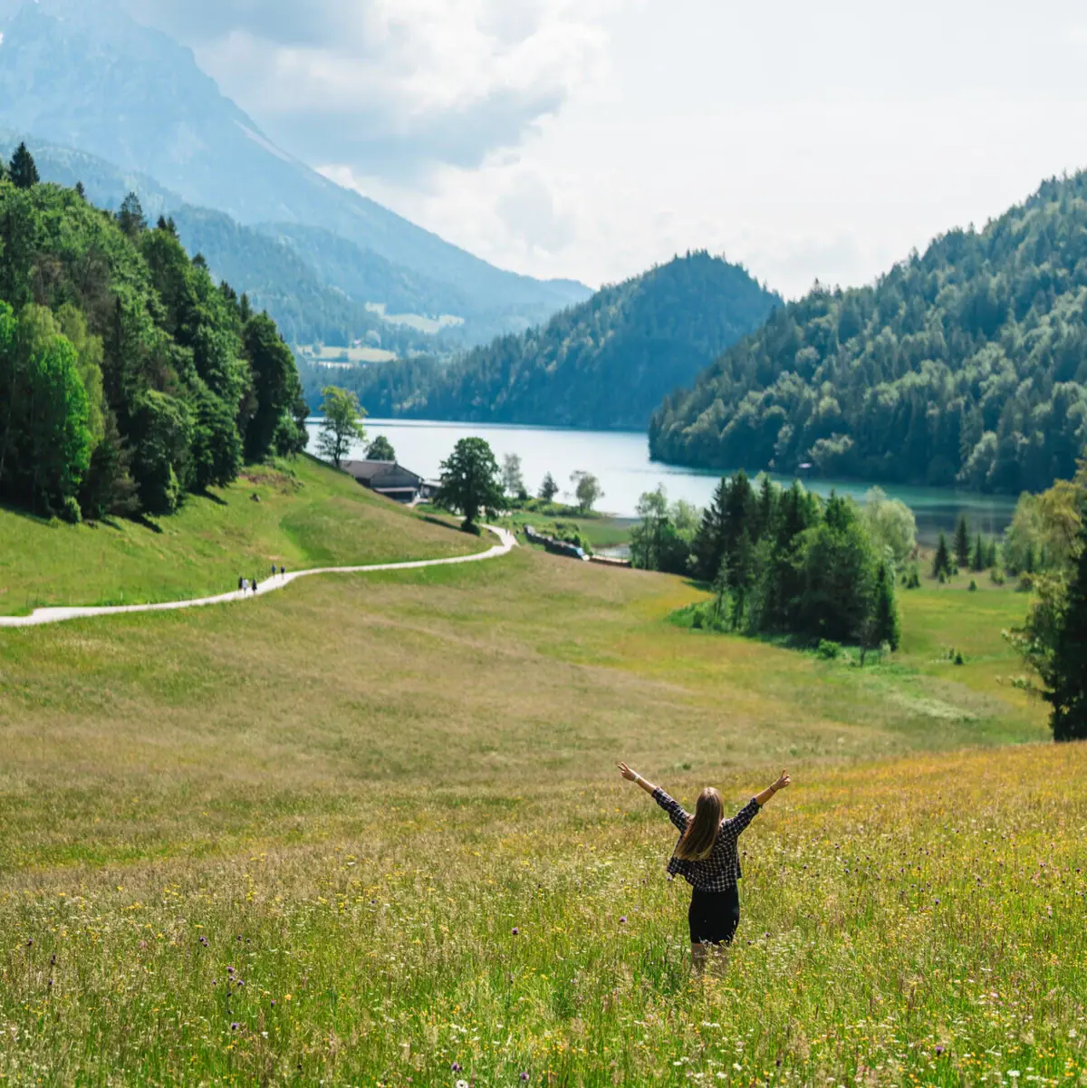 Eine Frau steht mit erhobenen Armen in einem Feld.