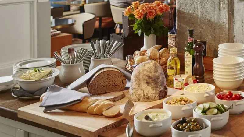 Auf einem Tisch liegt ein Schneidebrett mit Brot sowie einige Schälchen mit Speisen.