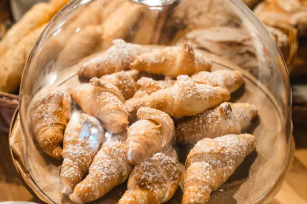 Ein Teller mit Croissants, bestäubt mit Puderzucker.