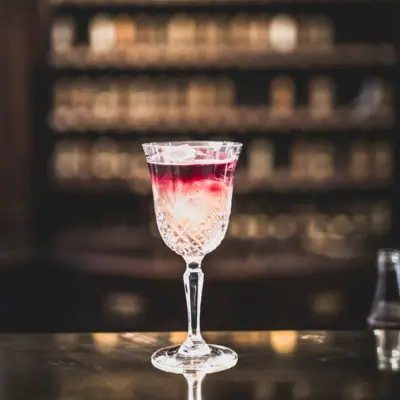 Ein Glas mit einem Getränk auf einer Bar.