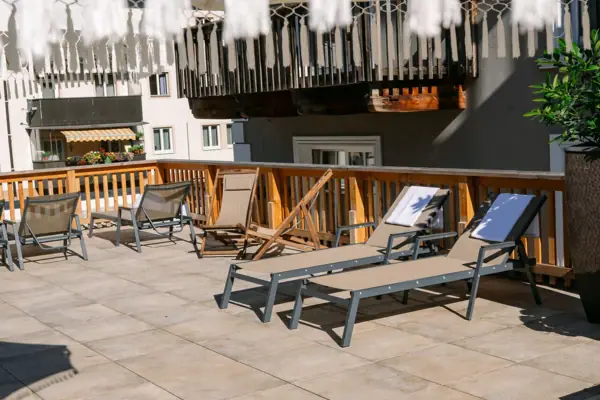 Sonnenterrasse Eine Terrasse mit Stühlen und einem weißen Sonnenschirm.