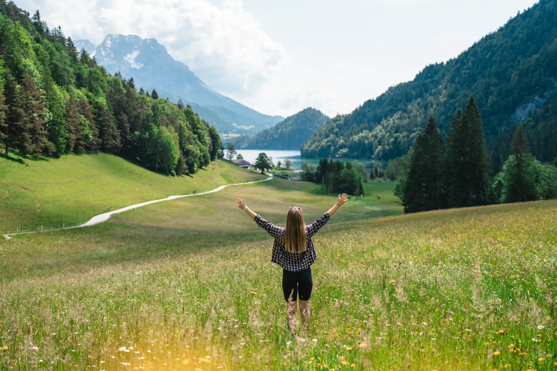 Hintersteiner See in Kitzbühel Eine Frau steht in einem Feld mit erhobenen Armen.