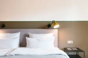 Ein Bett mit weißen Kissen vor einer zwei-farbigen Wand im HENRI Hotel Garmisch-Partenkirchen.