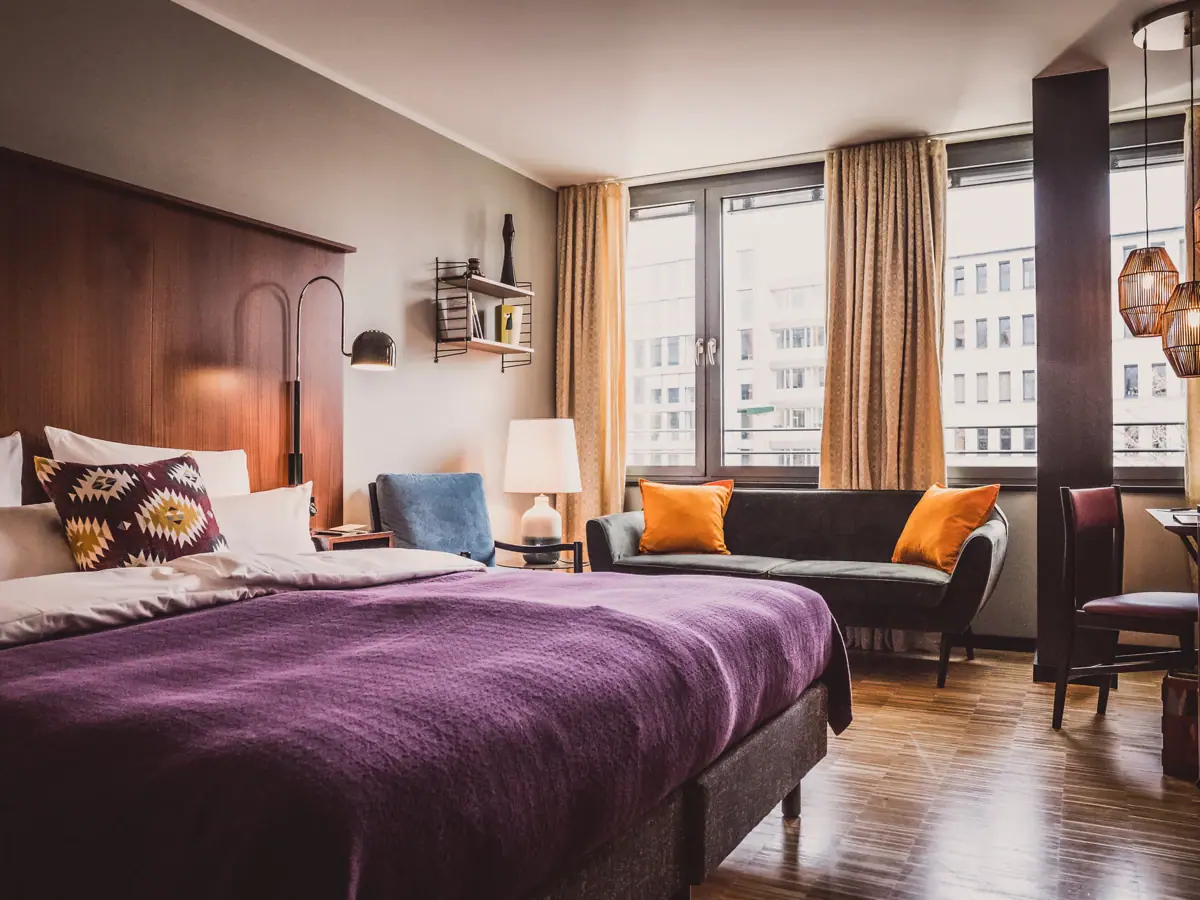 HENRI Düsseldorf Schlafzimmer mit lila Bett und Couch.