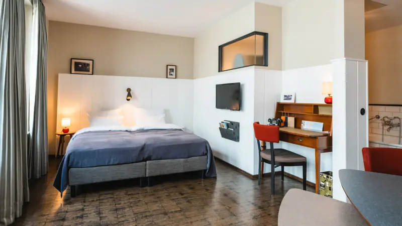 Zimmer mit Bett und Schreibtisch iim HENRI Hotel Hamburg.